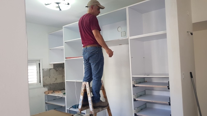 התקנת ארון שירות גדול בהתאמה אישית במהלך עבודת נגרות בבית